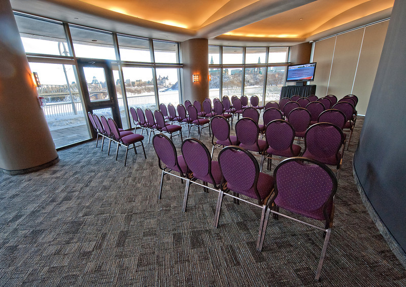 A large room with purple chairs and a tv.