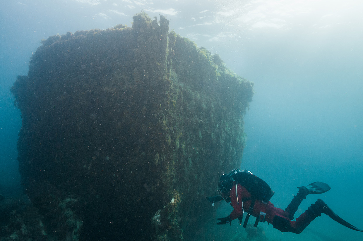 A diver is scuba diving near a shipwreck.