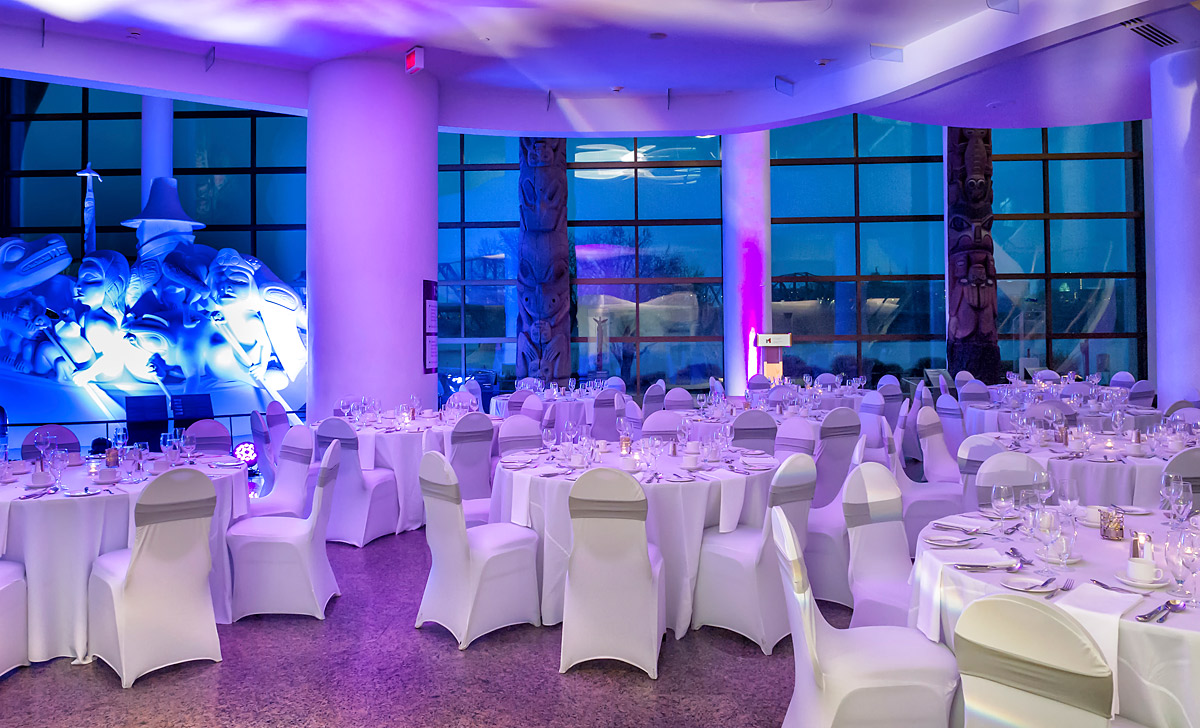 Une salle avec tables et chaises aménagées pour une réception de mariage à Ottawa au Musée canadien de l'histoire.