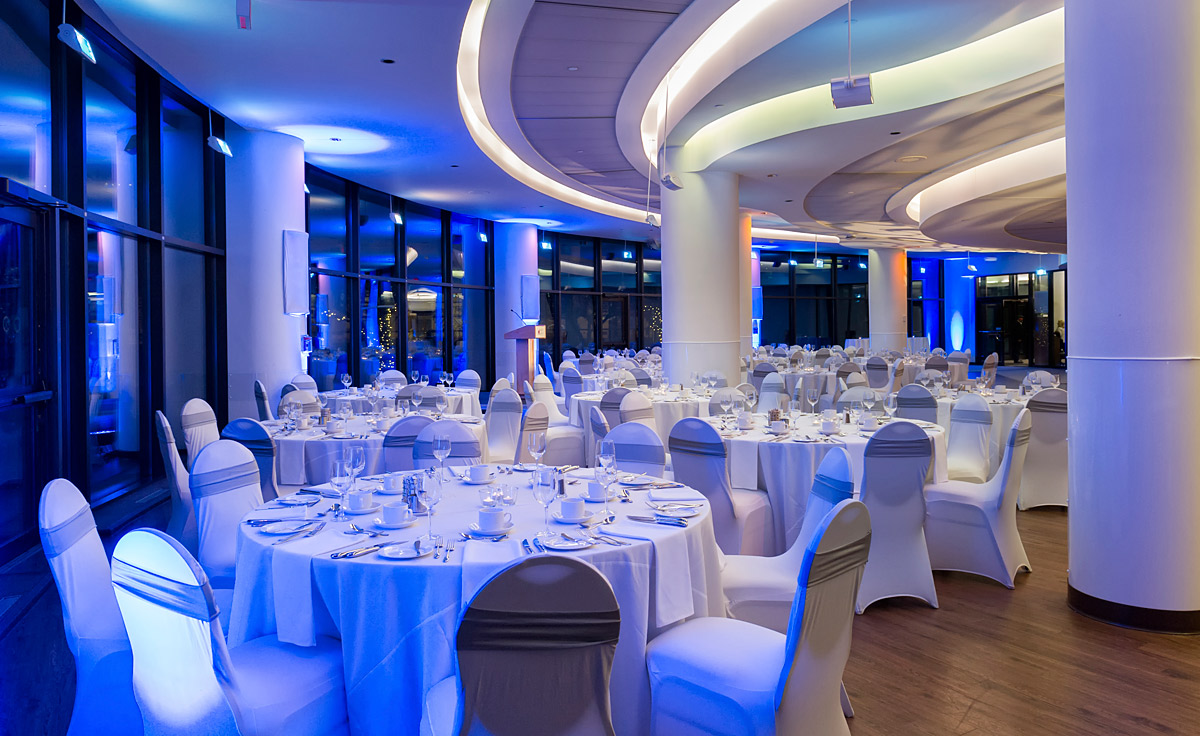 Une salle de banquet avec tables blanches et lumières bleues située à Ottawa, près du Musée canadien de l'histoire.