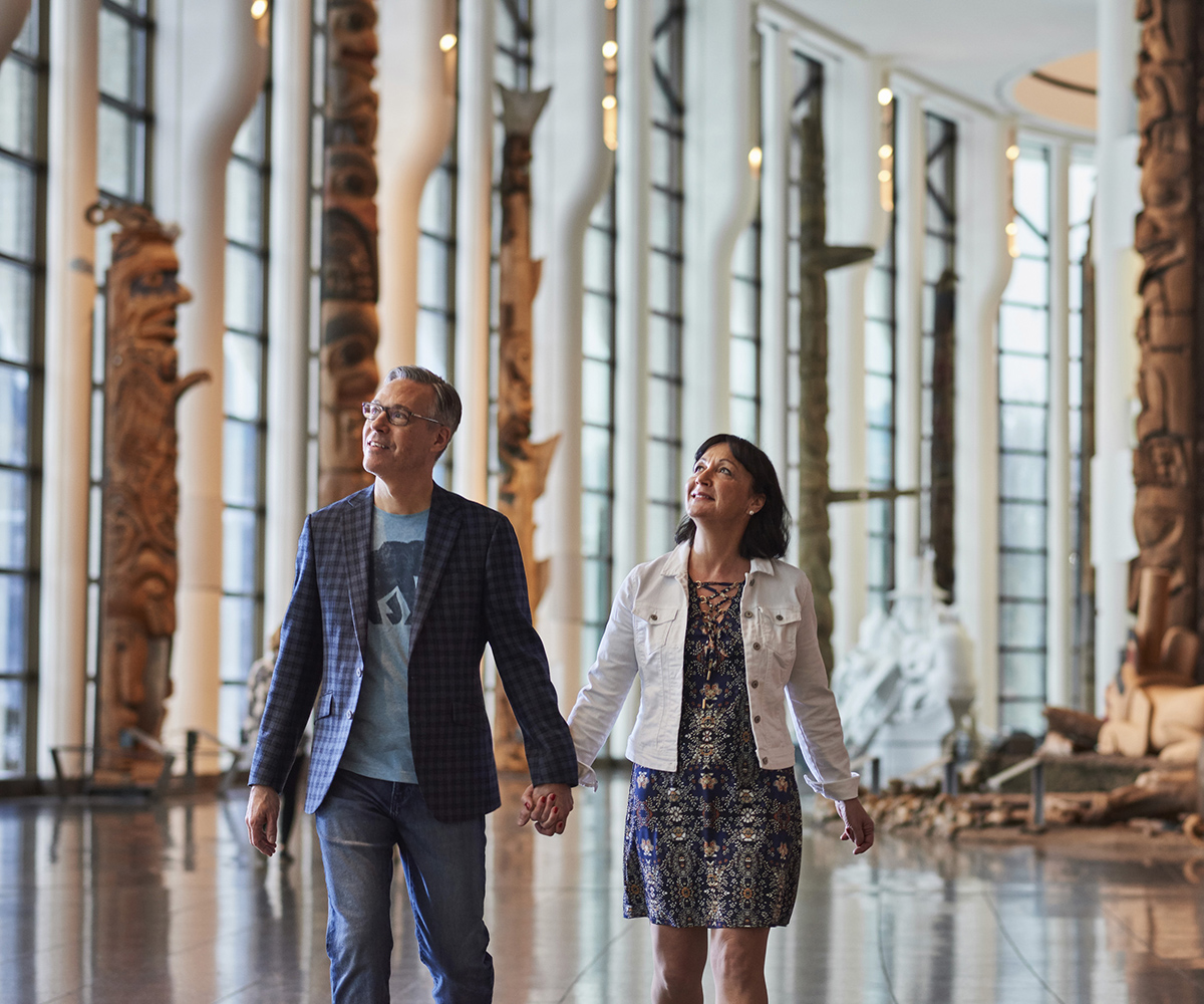 Un homme et une femme explorant le Musée canadien de l'histoire à Ottawa, admirant les impressionnants totems.