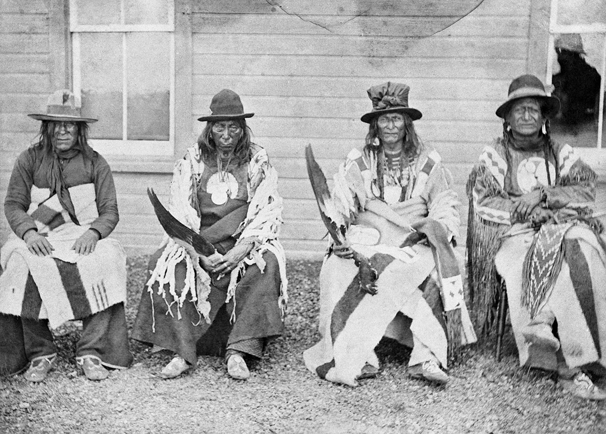 Un groupe d'Amérindiens assis devant une maison du Musée canadien de l'histoire, à Ottawa.