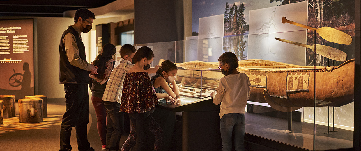 Un groupe de personnes à Ottawa regardant une exposition de canots au Musée canadien de l'histoire.