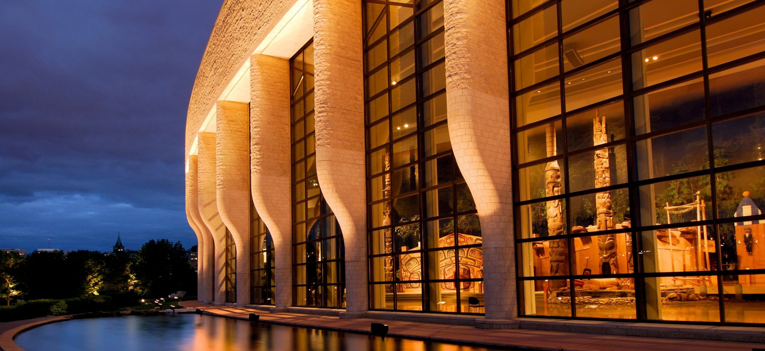 Le Musée canadien de l'histoire à Ottawa présente un bâtiment doté de grandes fenêtres et d'un jeu d'eau qui semble enchanteur la nuit.