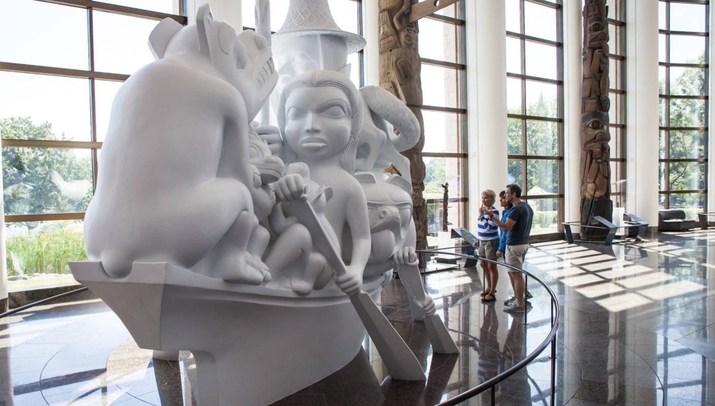 Un groupe de personnes debout devant une sculpture blanche au Musée canadien de l'histoire à Ottawa.