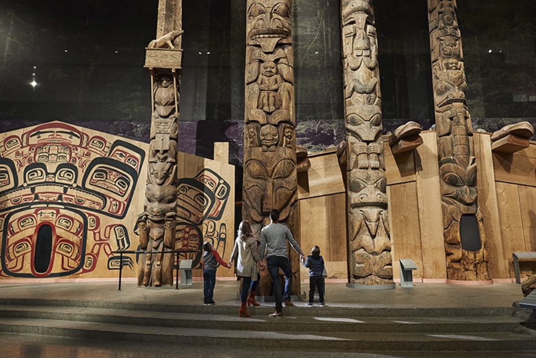 Un groupe de personnes debout devant des totems au Musée canadien de l'histoire à Ottawa.