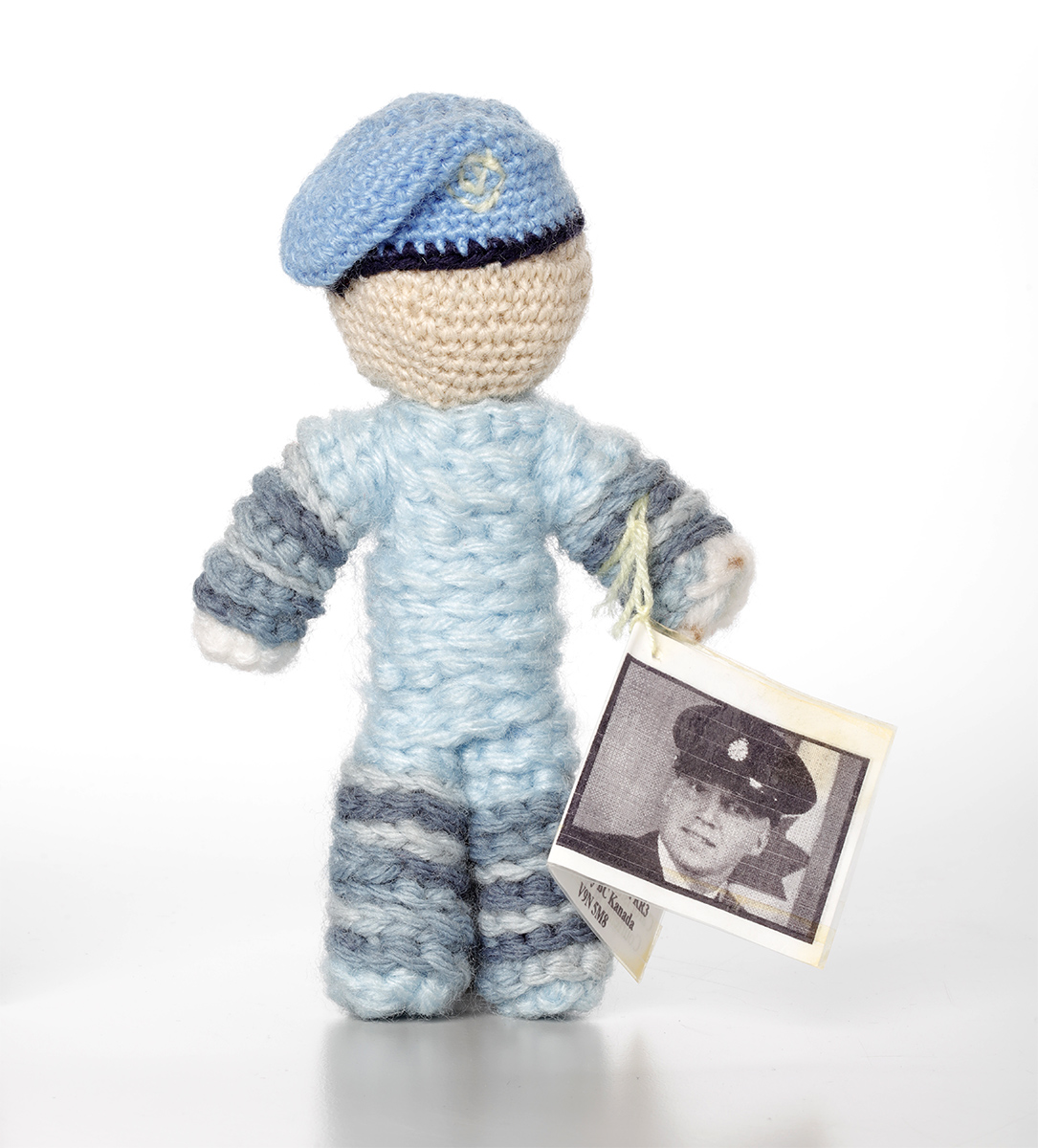 Une poupée au crochet avec une photo et un chapeau bleu exposée au Musée canadien de l'histoire à Ottawa.