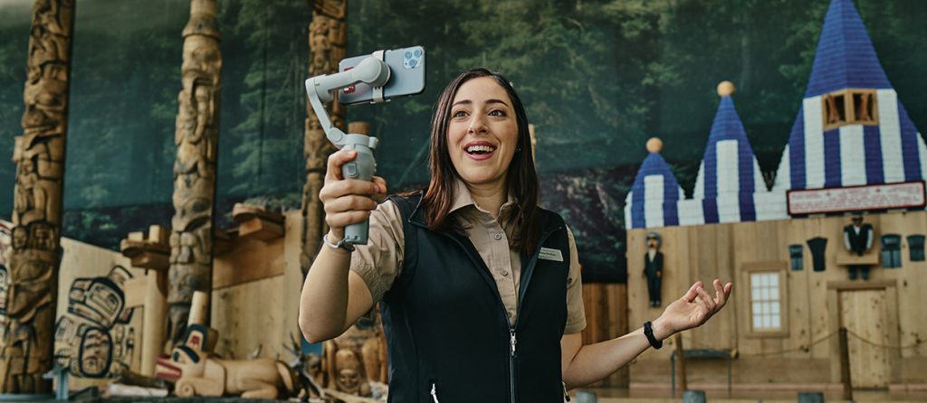 A woman holding a phone in front of an exhibit at the Canadian Museum of History.