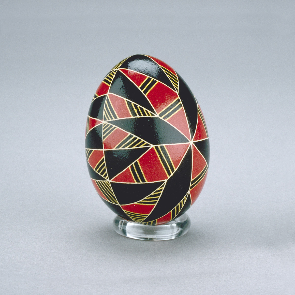 A black, red, and gold painted easter egg on display.