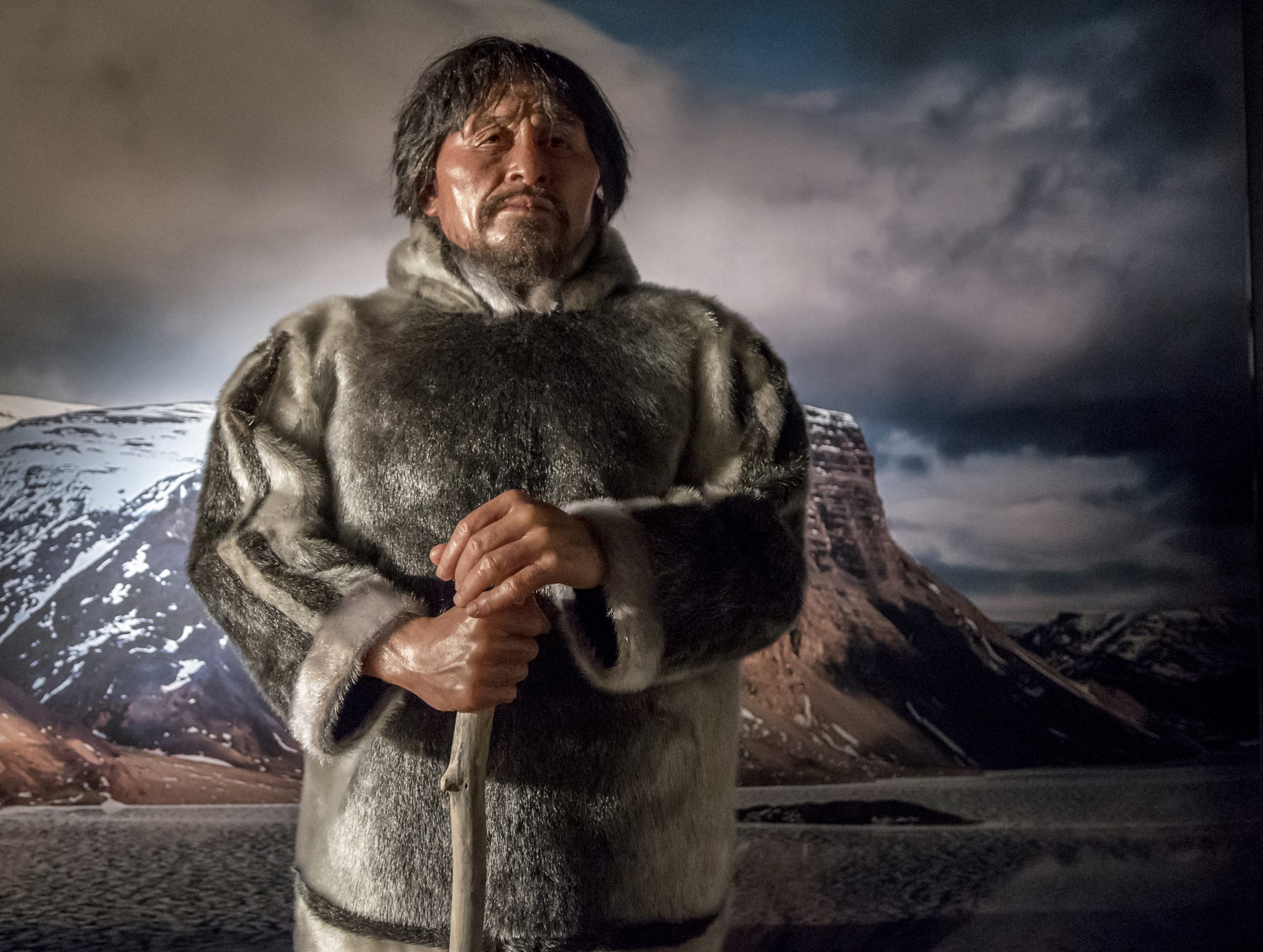 Un homme vêtu d'un manteau de fourrure debout devant une montagne au Musée canadien de l'histoire à Ottawa.