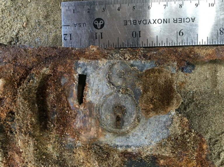 A ruler measuring the rust metal box's lock.