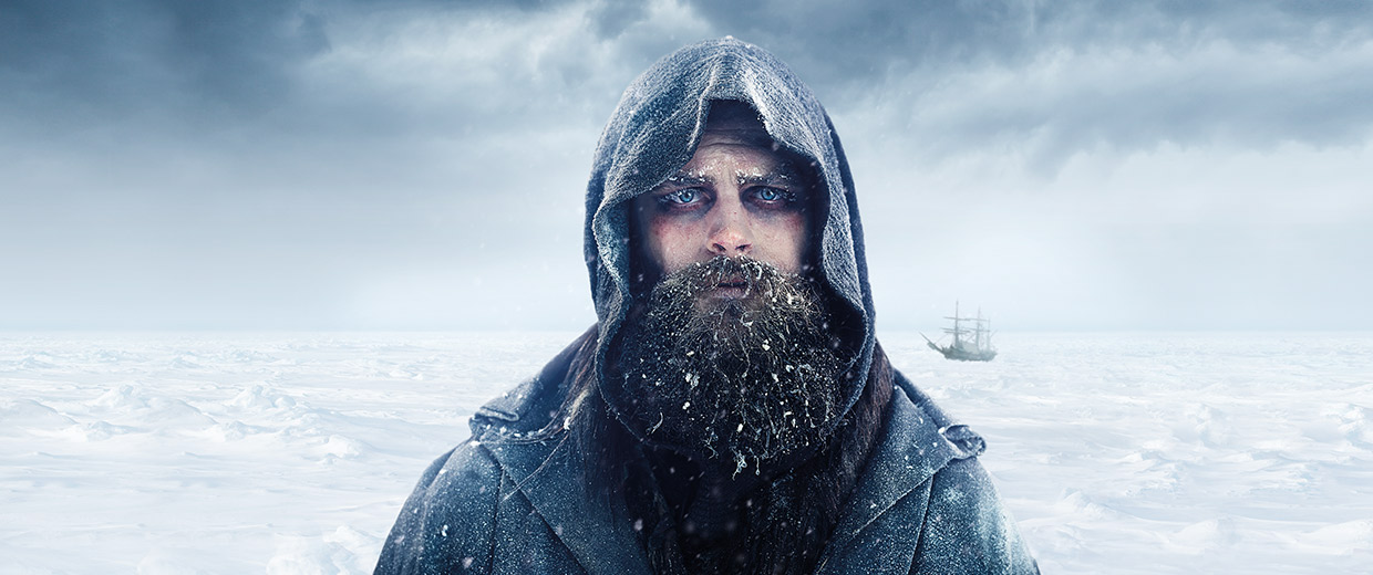 A bearded man with a hood on in the arctic.