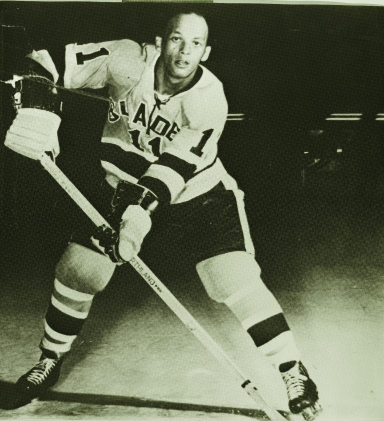 Stan “Chook” Maxwell poses with his stick on the ice, wearing his hockey equipment.